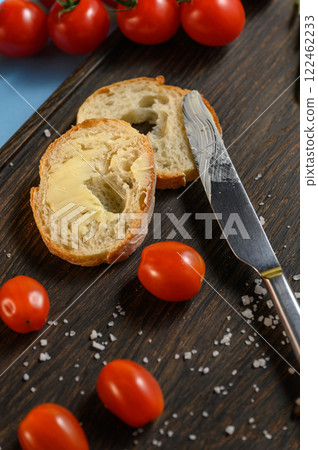 Bread with Butter, Tomatoes, and Knife on a Wooden Board Bread with Butter, Tomatoes, and Knife on a Wooden Board 122462233