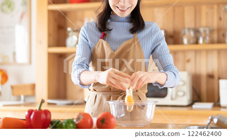 Smiling woman cooking in the kitchen (cracking a raw egg) Smiling woman cooking in the kitchen (cracking a raw egg) 122462400
