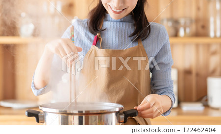Smiling woman cooking in the kitchen Smiling woman cooking in the kitchen 122462404