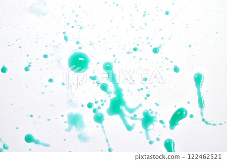 Drops of blue paint are scattered chaotically across a white sheet of paper. 122462521