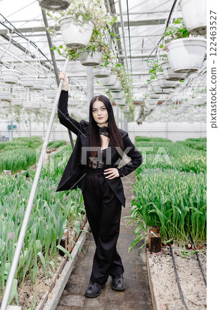 Young woman standing in large greenhouse with tulips Young woman standing in large greenhouse with tulips 122463527