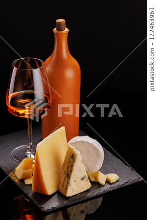 A refined selection of aged cheeses presented on a board, accompanied by a glasses of wine A refined selection of aged cheeses presented on a board, accompanied by a glasses of wine 122463961