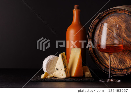 A refined selection of aged cheeses presented on a board, accompanied by a glass of wine 122463967