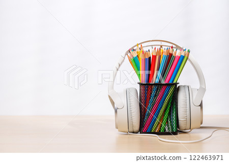 A desk organizer holding colorful pencils and headphones 122463971
