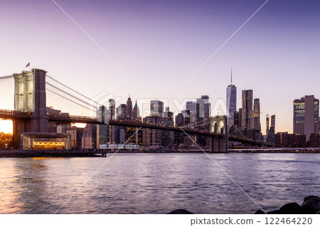 A panoramic sunset view of the Brooklyn Bridge stretching towards Manhattan 122464220