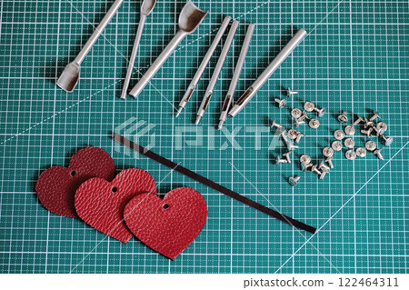 Tanners green cutting mat with work tools and red leathers hearts, close-up, selective focus. 122464311