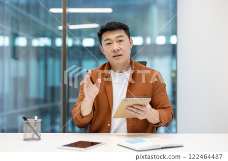 Asian man explaining concepts confidently. The business meeting setting highlights cooperation and teamwork. 122464487