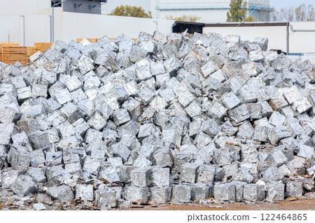 tacks of pressed aluminum cubes glisten in bright light, hinting at large-scale recycling operations. Reflective surfaces highlight an industrial push toward sustainability and efficient resource use 122464865