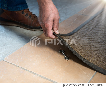 A person getting a key from under their mat A person getting a key from under their mat 122464892