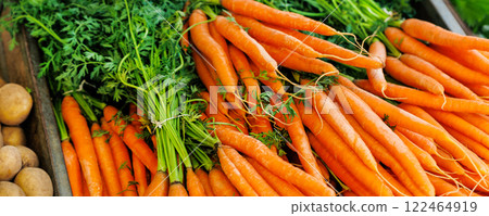 Close-up view fresh juicy clean orange local farmer's carrot bunch and potato street market retail counter stall sunny day. Local domestic organic plant vegetables at store. Sustainable agriculture Close-up view fresh juicy clean orange local farmer's carrot bunch and potato street market retail counter stall sunny day. Local domestic organic plant vegetables at store. Sustainable agriculture 122464919