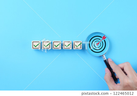 Business Strategy Planning and Quality Management Concept. Magnifying glass focuses on target icon and blocks with check marks. business goal setting, strategy planning, quality management processes, Business Strategy Planning and Quality Management Concept. Magnifying glass focuses on target icon and blocks with check marks. business goal setting, strategy planning, quality management processes, 122465012