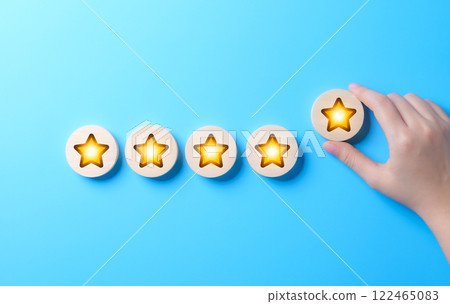 Customer satisfaction and feedback rating concept. A hand places a five-star rating on row of glowing stars, representing customer reviews, satisfaction, and feedback for quality services or products. 122465083