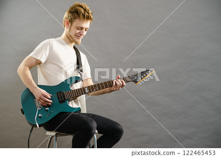 Young man playing electric guitar 122465453