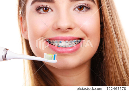 Woman brushing teeth with braces using brush Woman brushing teeth with braces using brush 122465578