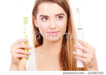 Woman with braces holding electric and traditional toothbrush 122465593