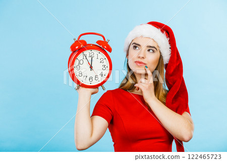 Woman wearing Santa Claus costume holding clock Woman wearing Santa Claus costume holding clock 122465723