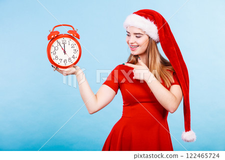 Happy woman wearing Santa Claus costume holding clock 122465724