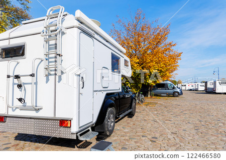 Back view pick-up off-road expedition truck parked many modern campervan recreational motor home vehicle camper park site Magdeburg city. Motorhome campground station travel destination. RV lifestyle 122466580