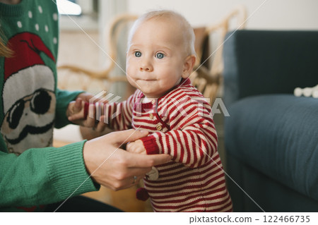 An Adorable Baby Dressed in Festive Holiday Attire is Joyfully Learning to Stand Up An Adorable Baby Dressed in Festive Holiday Attire is Joyfully Learning to Stand Up 122466735