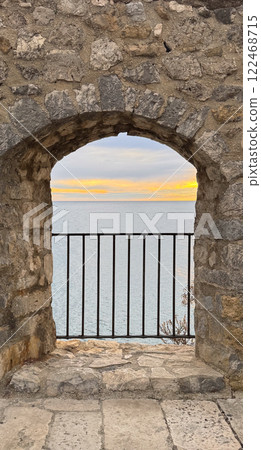 Stone Archway Overlooking Calm Sea at Sunset  122468715