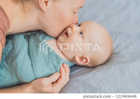 A mother gently wraps her baby in a soft muslin swaddle, providing warmth and comfort. A tender moment of care and love between mother and child. Motherhood, baby care, and nurturing concept A mother gently wraps her baby in a soft muslin swaddle, providing warmth and comfort. A tender moment of care and love between mother and child. Motherhood, baby care, and nurturing concept 122469446