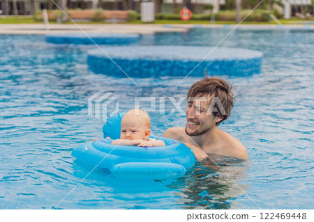 A father enjoys swimming in a pool with his son infant, who is safely placed in an inflatable baby float. Fun family bonding, summer relaxation, and parenting concept 122469448