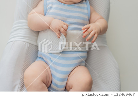 Adorable 3-month-old baby lying safely in a cozy infant cocoon secured with a special safety belt. Comfortable and protective design for newborn care. Parenting, safety, and baby comfort concept 122469467