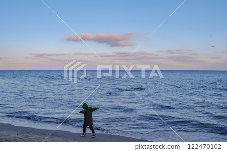 The child feels unity with nature. A little boy, arms outstretched, runs joyfully along the surf line. 122470102