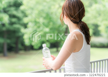 Young Asian woman drinking mineral water in the park/forest Young Asian woman drinking mineral water in the park/forest 122470221