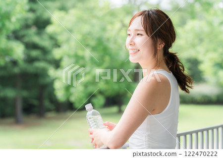 Young Asian woman drinking mineral water in the park/forest 122470222