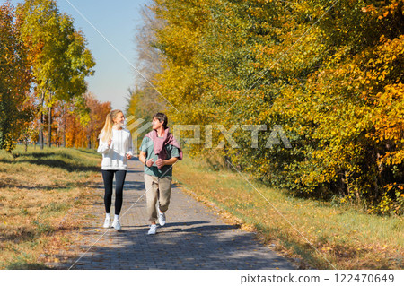Sporty family couple morning jogging in city autumn beautiful park. Young active man, woman runners 122470649