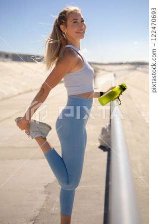 Woman runner jogger stretching leg physical exercise at river embankment closeup Woman runner jogger stretching leg physical exercise at river embankment closeup 122470693