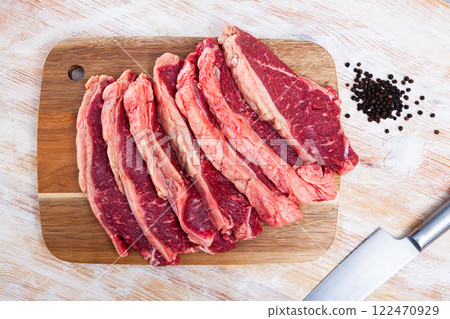 Sliced pieces of raw beef tenderloin on wooden cutting board 122470929