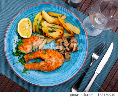 Deliciously steak of fried salmon with potatoes and mushrooms Deliciously steak of fried salmon with potatoes and mushrooms 122470930