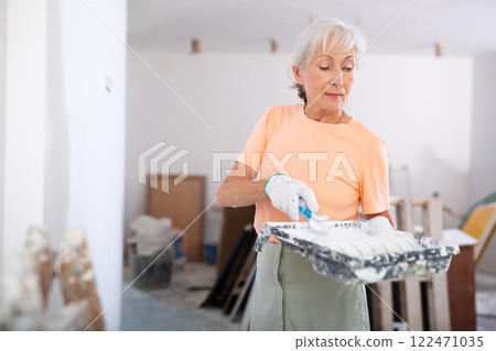 Mature woman painting wall, diy renovating home 122471035