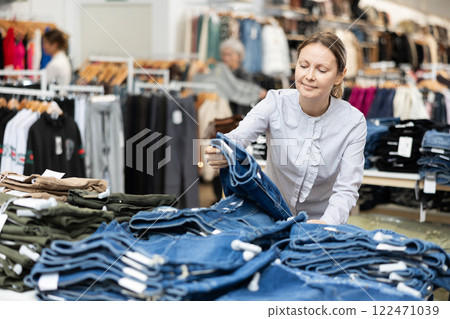 Adult woman choosing jeans in store Adult woman choosing jeans in store 122471039