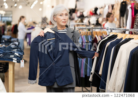 Elderly woman trying on a new jacket in clothing boutique 122471068