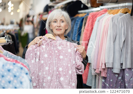 Elderly woman chooses pajamas in store Elderly woman chooses pajamas in store 122471070