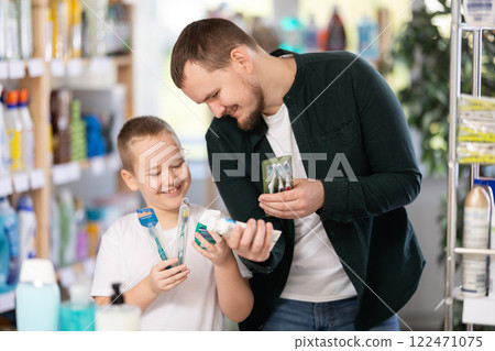 Schoolboy son and dad are choosing toothbrush in store 122471075