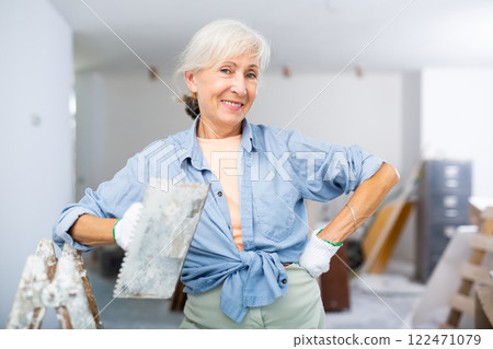 Portrait of positive woman with spatula in her hand in room being renovated Portrait of positive woman with spatula in her hand in room being renovated 122471079