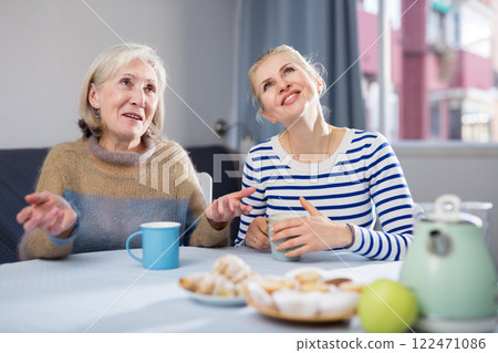 Mature mother and her adult daughter drink tea and chat Mature mother and her adult daughter drink tea and chat 122471086
