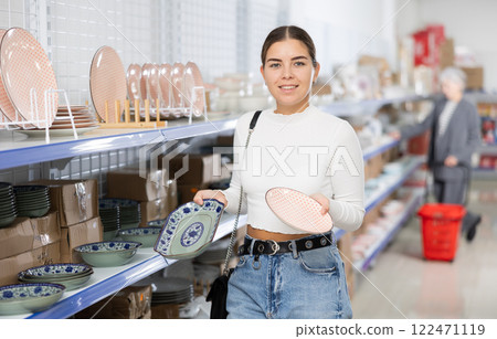 Young woman in supermarket is choosing plates with Asian pattern 122471119