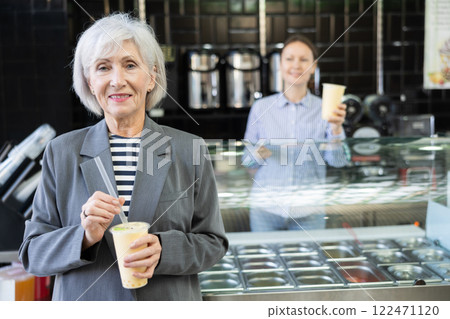 Senior woman drinks tonic bubble tea through straw 122471120