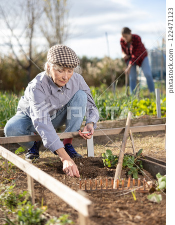 Female owner of plantation planting seeds on beds 122471123