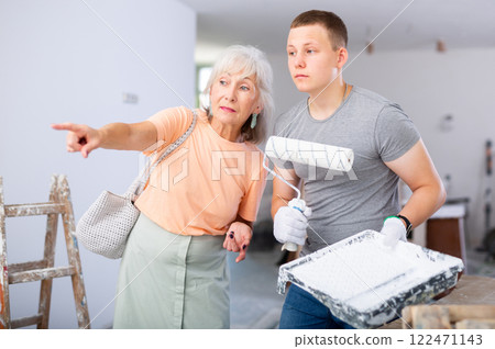 Guy helps his grandmother to renovate the room during holidays. Grandma points with her finger what to do 122471143