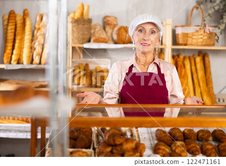 senior bakery worker sells croissants and shows off a variety of crescent-shaped buns. senior bakery worker sells croissants and shows off a variety of crescent-shaped buns. 122471161