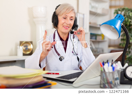 Female doctor in headphones with microphone consults patient on Internet Female doctor in headphones with microphone consults patient on Internet 122471166