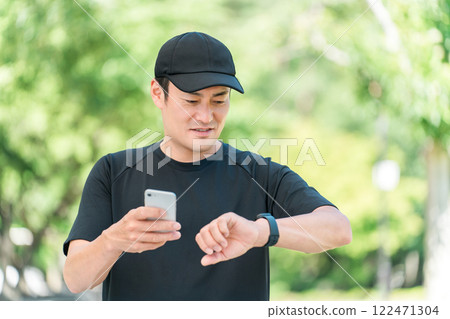 A middle-aged man in sportswear using a smartwatch to manage his health and health care 122471304