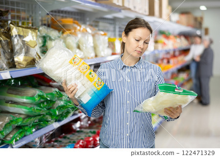 Positive woman choosing noodles for dinner in Asian food store Positive woman choosing noodles for dinner in Asian food store 122471329