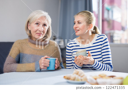 Mature mother and her adult daughter drink tea and chat 122471335